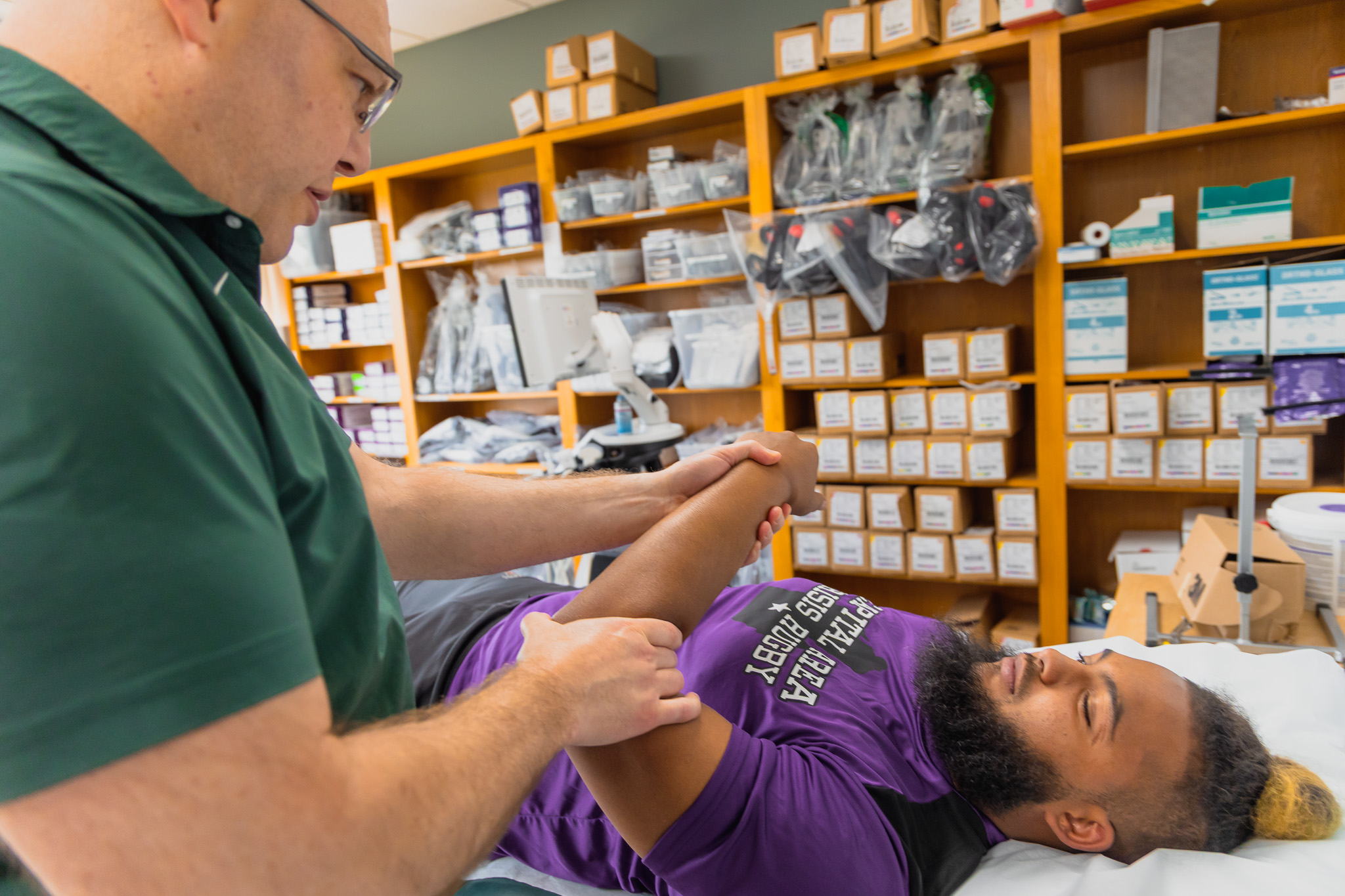 a sports medicine doctor evaluating an injury of a rugby player in clinic